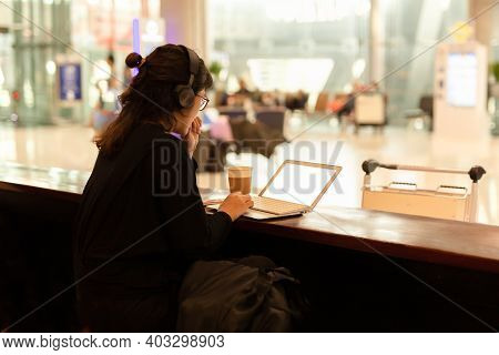 Tourist Woman With Headphone Working On Laptop In A Coffee Shop At The Airport