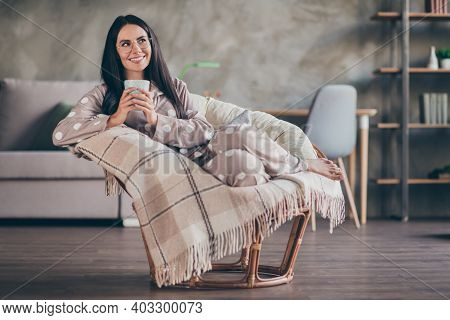 Photo Of Cute Optimistic Girl Lying Hold Cup Look Empty Space Wear Pijama Spectacles At Home