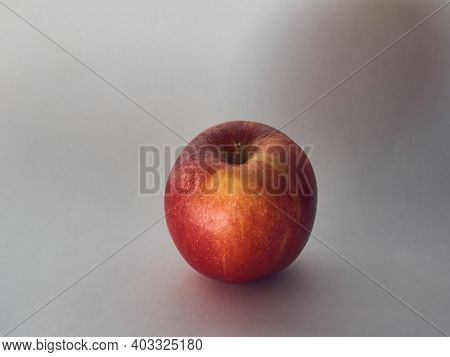 One Red, Ripe Apple On A White Background, The Light Is Diffused, Muffled.