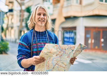 Young scandinavian tourist man smiling happy using map at the city.
