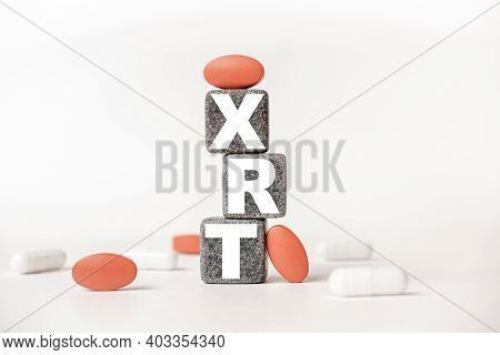 A Group Of White And Red Pills And Cubes With The Word Xrt Radiotherapy External On Them, White Back