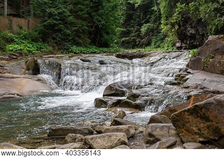 A Tiny River In The Mountain Forest With Low Water Waterfall. Brite Summer Day In Mountain Forest.