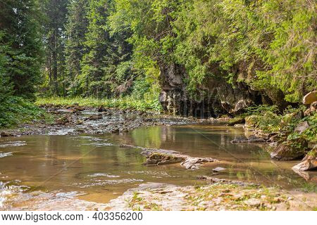 A Tiny River In The Mountain Forest With Low Water Waterfall. Brite Summer Day In Mountain Forest.