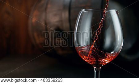 Pouring red wine into wine glass on dark background, still life background