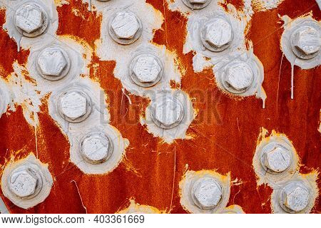Abstract Background Of Bolts And Nuts Painted White On A Red Background