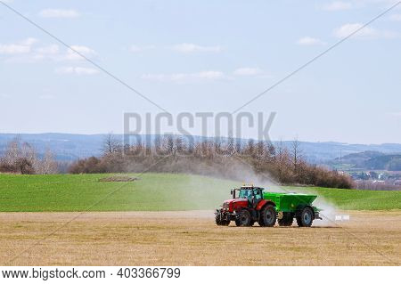 Agricultural Work. Tractor Spreading Fertilizer On Grass Field.