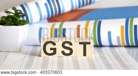 Gst Word Concept Written On Wooden Blocks, Cubes On A Light Table With Flower ,pen And Glasses On Ch