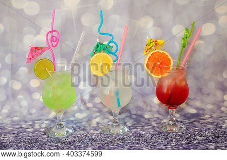 Three Glasses With Citrus Juices Of Lime, Grapefruit And Lison Stand On A Gray Background, Decorated