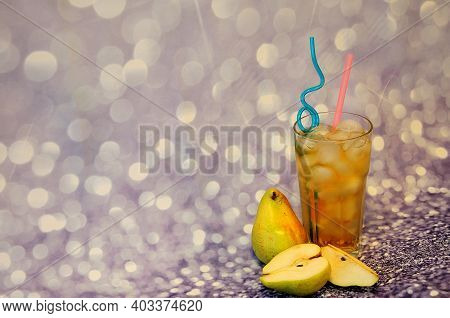 A Tall Glass Of Pear Juice With Ice Stands On A Gray Background.