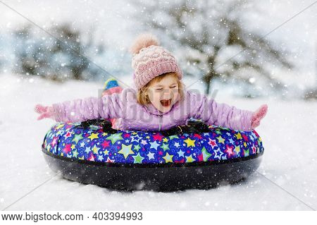 Active Toddler Girl Sliding Down The Hill On Snow Tube. Cute Little Happy Child Having Fun Outdoors 
