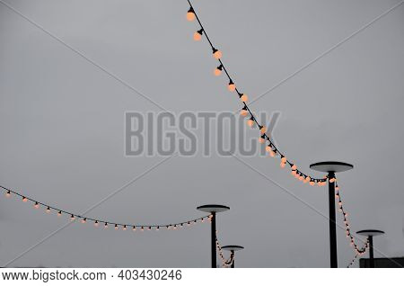 View Of Winter Snowy Slopes Of A Ski Resort With Lit Chains Of Light Bulbs. These Lights Are Used At