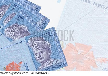 1 Malaysian Ringgit Bills Lies In Stack On Background Of Big Semi-transparent Banknote. Abstract Bus