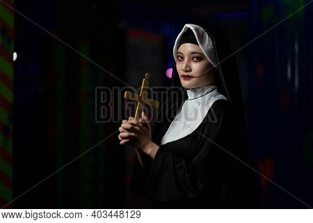 Scary Woman Devil Nun Holding A Cross. Horror Halloween Concept