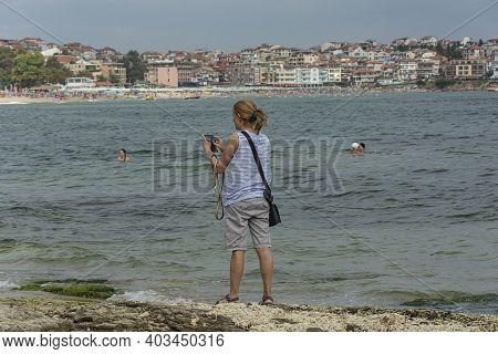 Bulgaria, Sozopol - 2018, 06 September: A Woman On The Beach With A Smartphone, Blurred Background. 