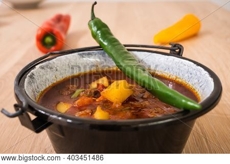 Hungarian Beef Goulash Or Gulyas Soup Or Stew Served In A Small Cauldron With Potatoes, Meat, Paprik