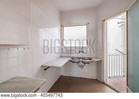 Bright Empty Kitchen With Tiled Floor And Walls Before Renovation