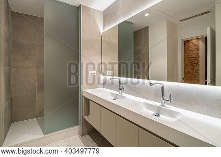 Modern Tiled Bathroom With A Shower Area, Two Sinks And A Big Wall Mirror
