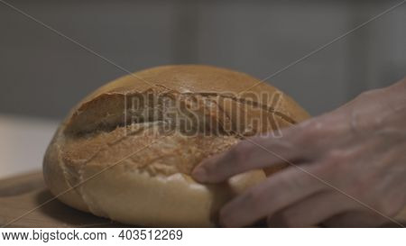 Close Up Of Female Hands Slicing White Bread In Slow Motion On A Wooden Board. Action. Cutting Fresh