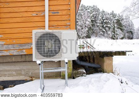 Air To Water Heat Pump Near An Old Wooden House In Winter. Air Water Heatpump Close Up
