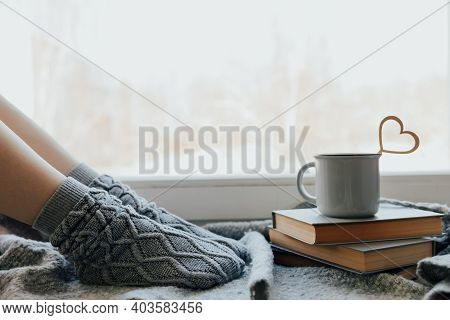 Cozy Winter Still Life: Woman Legs In Warm Woolen Socks Under Shaggy Blanket And Mug Of Hot Beverage