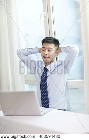 Portrait Of Young Bisinessman Strecthing In Office High Quality Photo