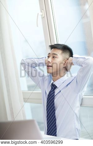 Portrait Of Young Bisinessman Strecthing In Office High Quality Photo