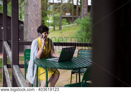 Young Woman Working On Computer From Home Office From A Cabin Or Cottage.