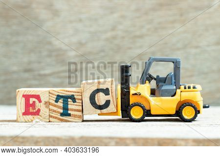 Toy Forklift Hold Letter Block C To Complete Word Etc (abbreviation Of Et Cetera) On Wood Background