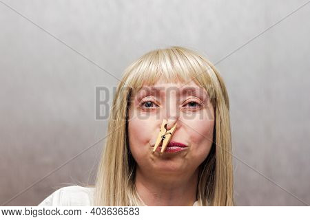 The Woman Covered Her Nose With A Clothespin. The Staged Photo Seems To Have A Strong Smelly Smell.
