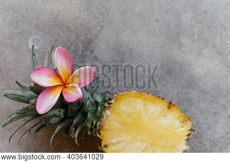 Pineapple And Frangipania On A Stone Table. Tropical Fruits. Top View. Free Space For Your Text.