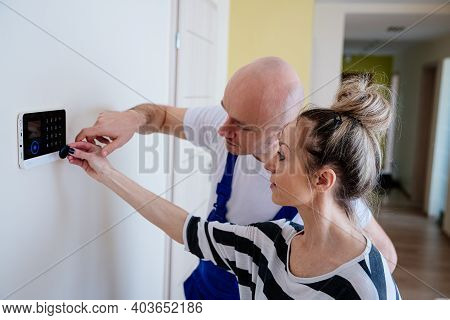 A Handsome Alarm Fitter Explains To The Woman How To Handle The Alarm. Protection Against Burglars.