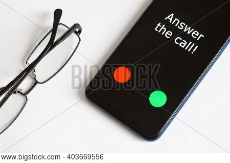 Black Smartphone With An Incoming Call And The Inscription: Answer The Call Lies On A White Backgrou