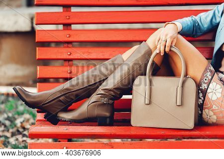 Autumn Fashion Image Of Young Woman Posing On The Red Bench, Wearing Blue Leather Jacket, Colourfull