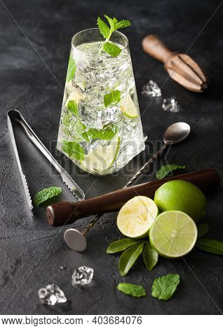 Highball Glass Of Mojito Cocktail With Ice Cubes,mint And Lime On Black Board With Spoon And Wooden 