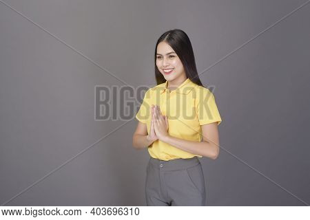 Beautiful Confident Woman Is Greeting (thai Wai) To Show Respect Over Grey Background Studio