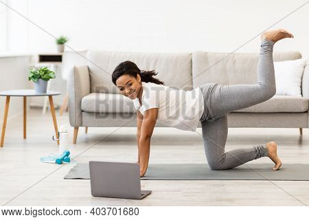 Online Workout. Fit Young African American Woman Excersising At Home, Watching Video Tutorial On Lap