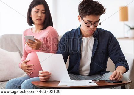 Concerned Asian Couple Calculating Expenses Looking At Invoice Bills Struggling Financial Crisis Sit