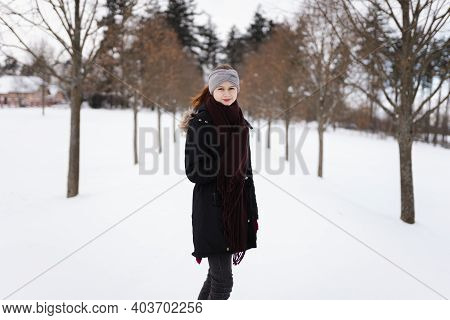Photo Of Happy Young Girl In Winter Clothes With Snow Staying On The Road