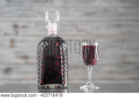 Homemade Tincture Of Red Cherry In A Glass Bottle And A Wine Crystal Glass , Ukraine, Close Up