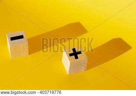 Plus And Minus On A Yellow Background. Business Concept.