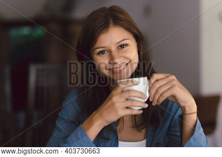 Young Girl In Cafe With Cup Of Hot Chocolade Smiling