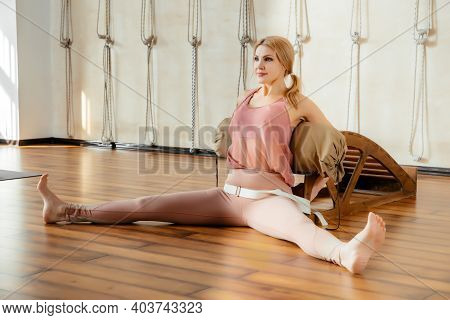 Mature Woman Doing Stretching Exercises On Yoga Backbend Bench In Studio