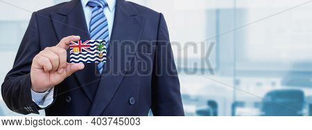 Cropped Image Of Businessman Holding Plastic Credit Card With Printed Flag Of British Indian Ocean. 