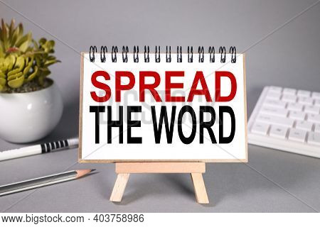 Spread The Word, Text On White Paper On Stand On Gray Background