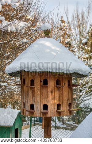 Wooden Dovecote With A Roof Cowered By Snow, A House For Pigeons Made Of Wood In The Garden As A Nes