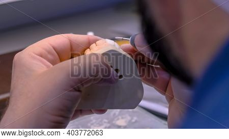 Professional Dental Technician Or Dentist Holding Motor Handpiece Tool And Working With Dental Prost