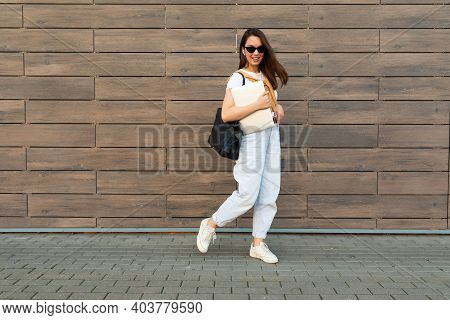 Full Length Photo Shot Of Young Charming Beautifyl Brunet Woman Going In The Street Near Brown Wall 