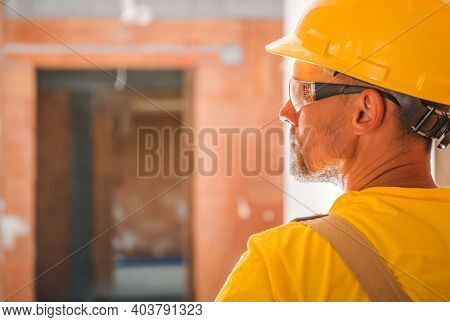 Yellow Uniform And Hard Hat Wearing Construction Worker Inside Newly Built Concrete Brick Commercial