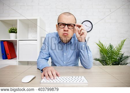 Eyevision Problems - Man Using Computer, Holding Glasses On His Face And Peering Into The Distance T