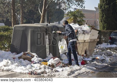 Madrid, Spain - January 17, 2021: A Man Tries To Throw Some Glass Bottles Into The Container, Among 